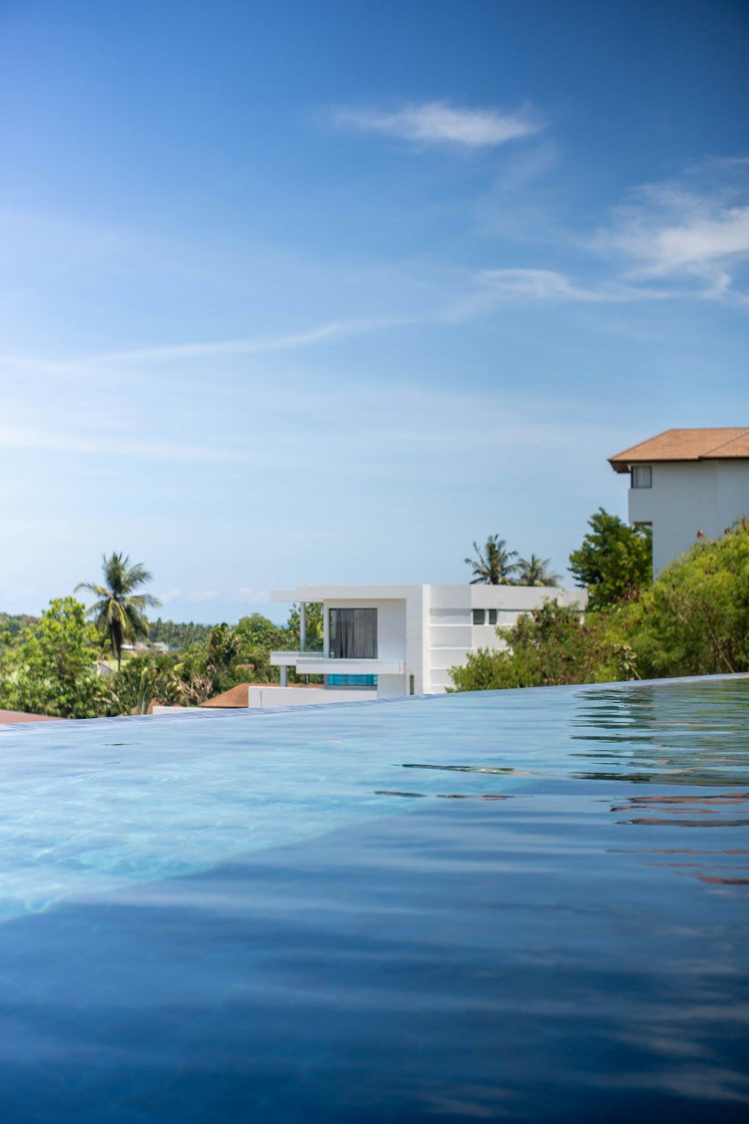 Modern minimalist villa exterior with infinity pool overlooking the ocean